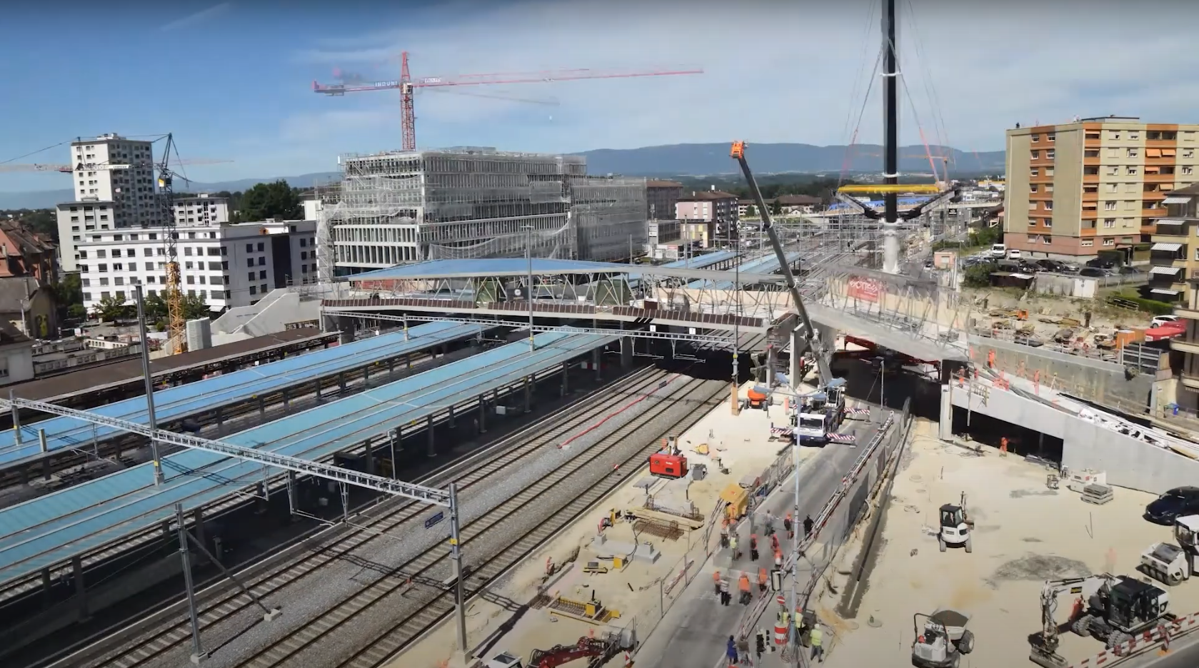 Ouvriers travaillant à la gare de Renens en construction avec passerelle.